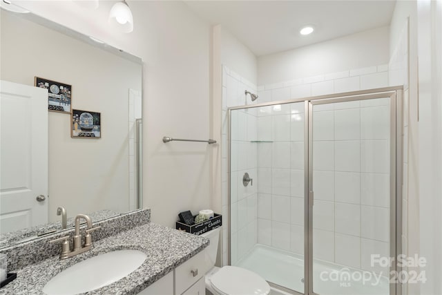 bathroom with vanity, toilet, and a shower with door