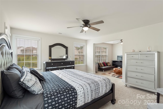 bedroom featuring multiple windows, ceiling fan, and light carpet