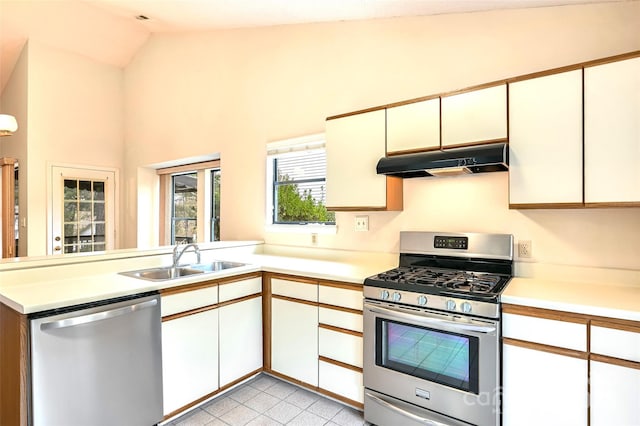 kitchen featuring lofted ceiling, kitchen peninsula, sink, appliances with stainless steel finishes, and white cabinetry