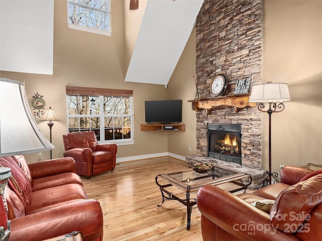 living area featuring a healthy amount of sunlight, light wood-style floors, a fireplace, and baseboards