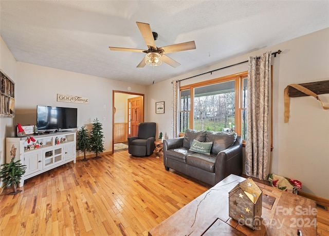 living room with ceiling fan, light hardwood / wood-style flooring, and a textured ceiling