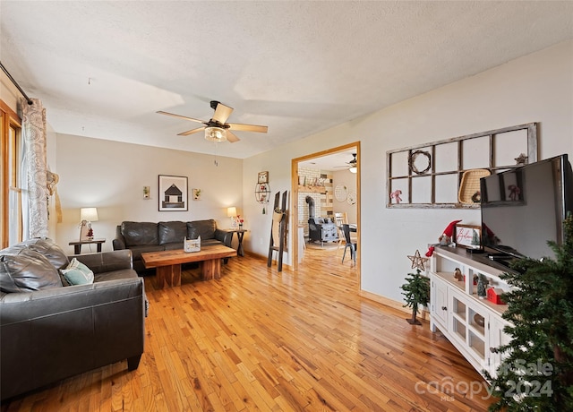 living room with hardwood / wood-style floors, ceiling fan, and a textured ceiling