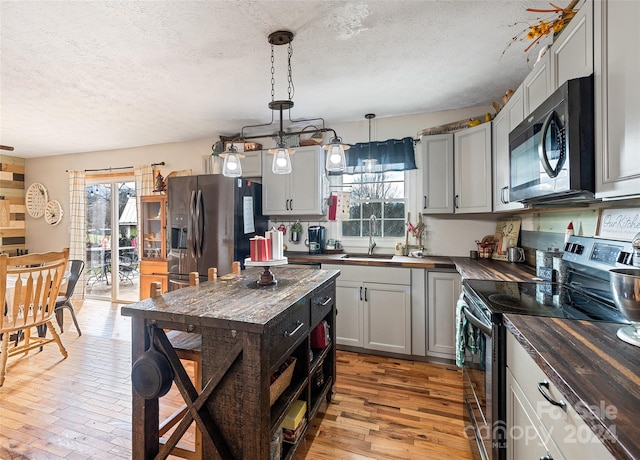 kitchen featuring plenty of natural light, wood counters, hanging light fixtures, and appliances with stainless steel finishes