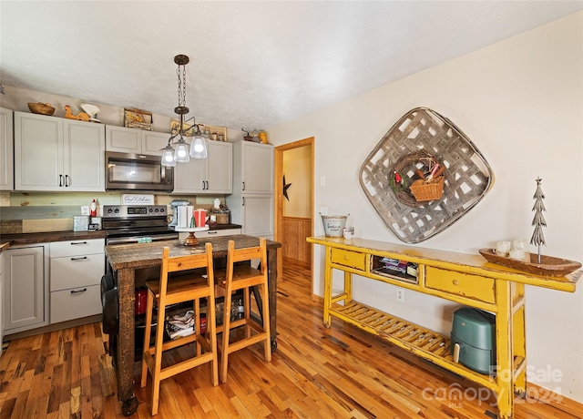 kitchen with gray cabinets, pendant lighting, stainless steel appliances, and wood-type flooring