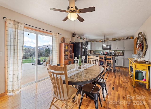 dining room with ceiling fan, a textured ceiling, and light hardwood / wood-style flooring