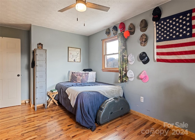 bedroom with ceiling fan, hardwood / wood-style floors, and a textured ceiling