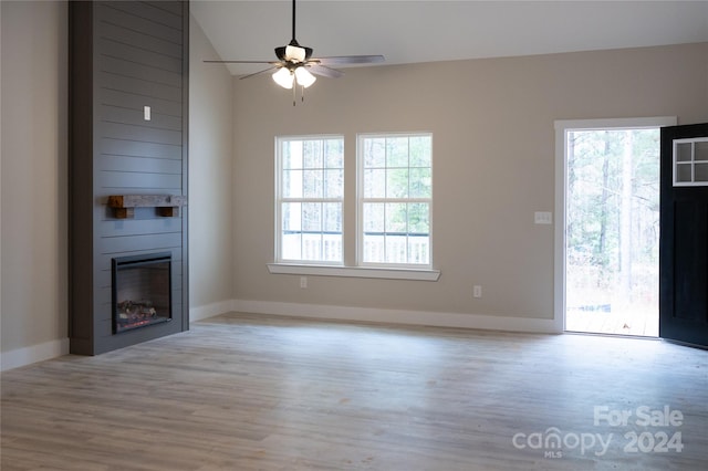 unfurnished living room featuring ceiling fan, light hardwood / wood-style floors, lofted ceiling, and a fireplace