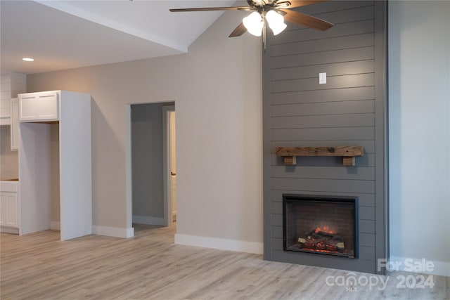 unfurnished living room with ceiling fan, a large fireplace, lofted ceiling, and light wood-type flooring