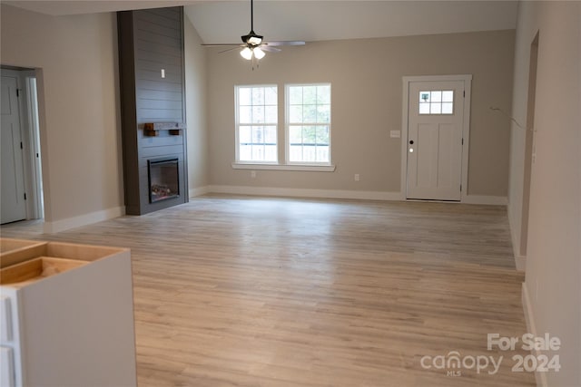 unfurnished living room with a large fireplace, ceiling fan, light hardwood / wood-style floors, and vaulted ceiling