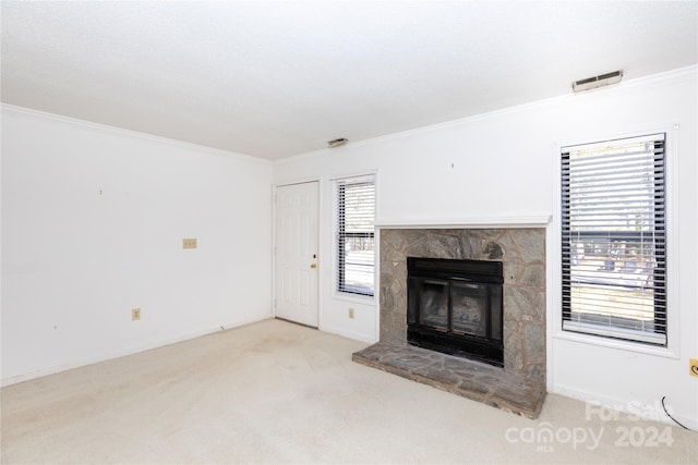 unfurnished living room featuring a stone fireplace, crown molding, and light colored carpet