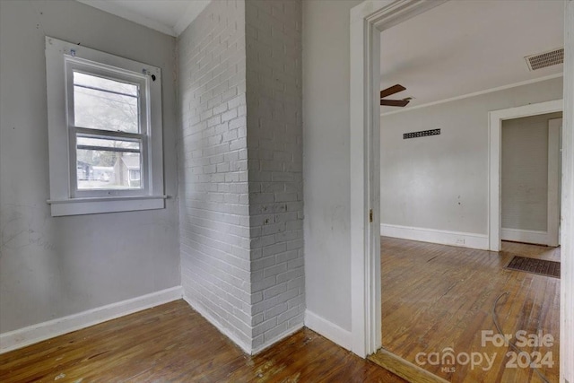 hallway with wood-type flooring and ornamental molding