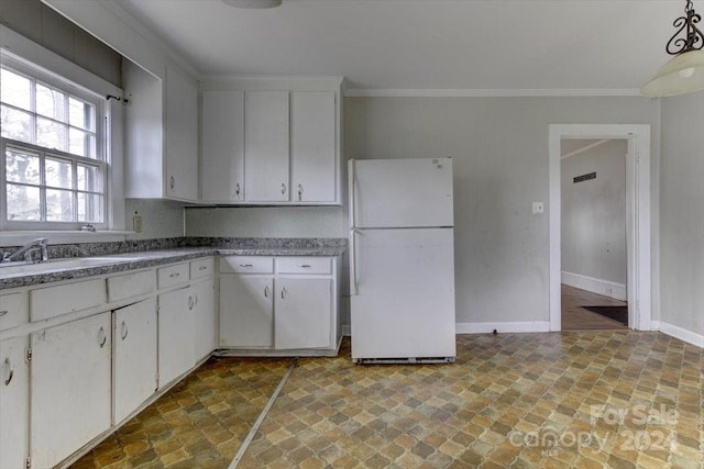 kitchen with white cabinetry, crown molding, white fridge, and sink