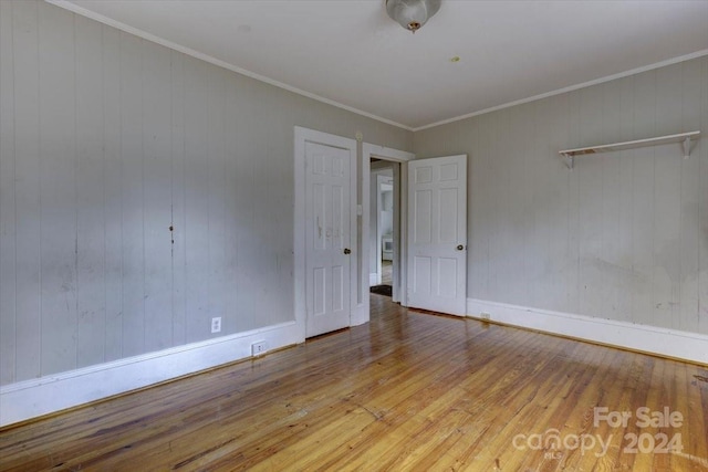 unfurnished room with crown molding, light hardwood / wood-style flooring, and wooden walls