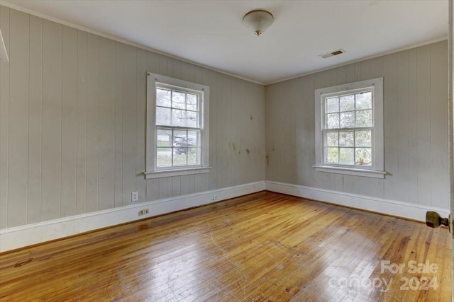 empty room with wood walls and light hardwood / wood-style floors