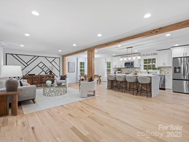 living room with beamed ceiling and light wood-type flooring