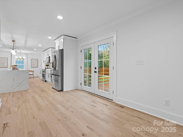 kitchen with appliances with stainless steel finishes, white cabinetry, hanging light fixtures, light stone counters, and french doors