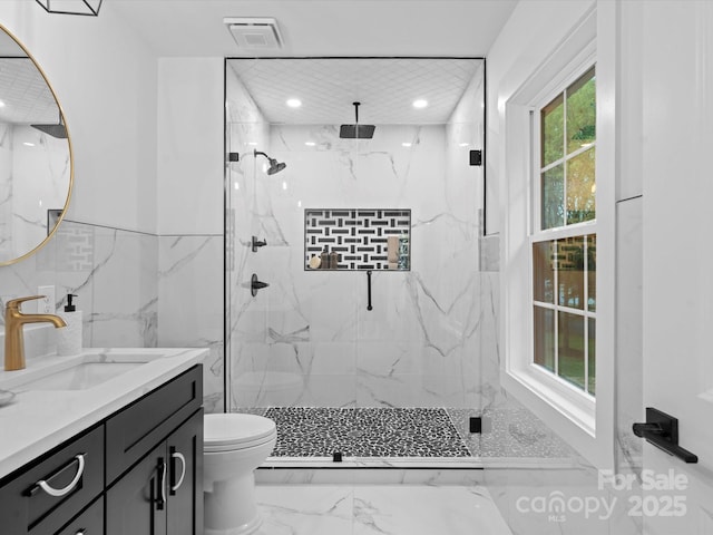 bathroom with a shower with door, vanity, tile walls, and toilet