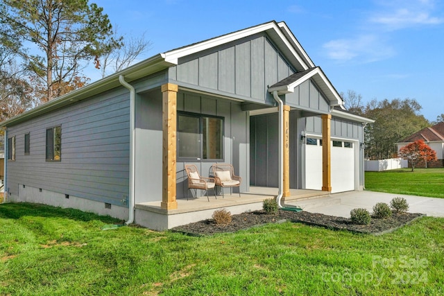 back of house featuring a lawn, a porch, and a garage