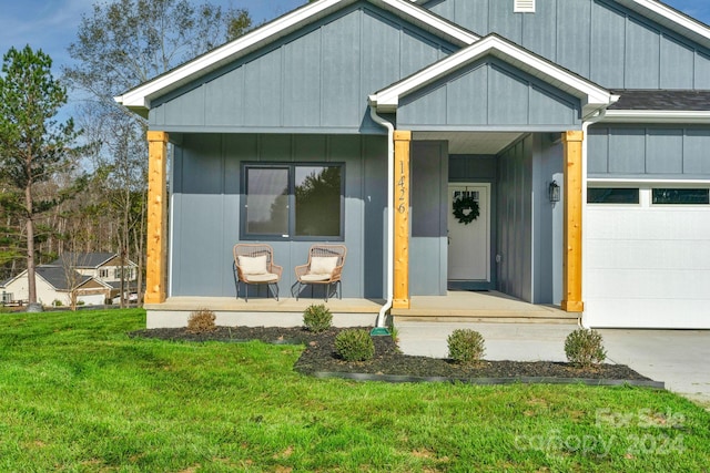 view of exterior entry featuring a lawn, covered porch, and a garage