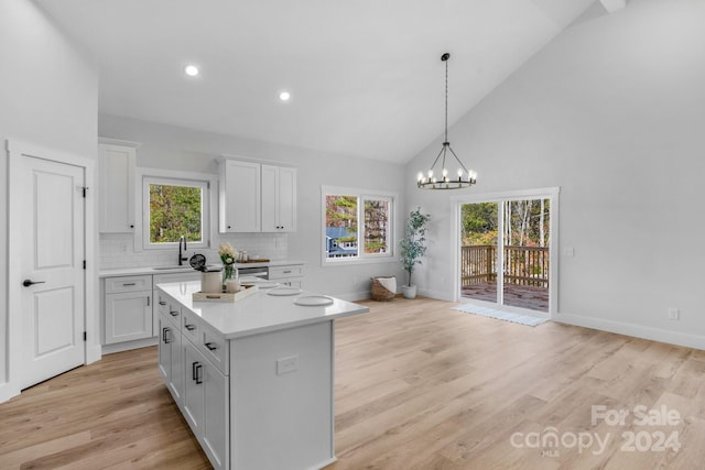 kitchen with a center island, sink, hanging light fixtures, light hardwood / wood-style floors, and white cabinets