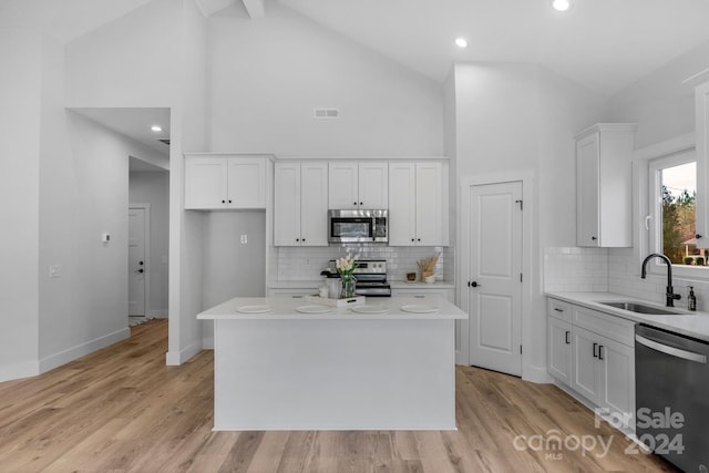 kitchen featuring white cabinetry, sink, stainless steel appliances, light hardwood / wood-style floors, and a kitchen island