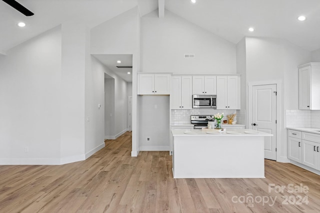 kitchen with a center island, backsplash, white cabinets, light wood-type flooring, and stainless steel appliances