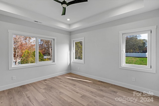 empty room featuring ceiling fan, a raised ceiling, and light wood-type flooring