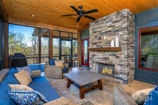 sunroom with ceiling fan, wooden ceiling, and an outdoor stone fireplace