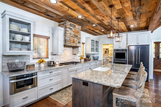 kitchen with white cabinetry, sink, dark wood-type flooring, a kitchen island with sink, and appliances with stainless steel finishes