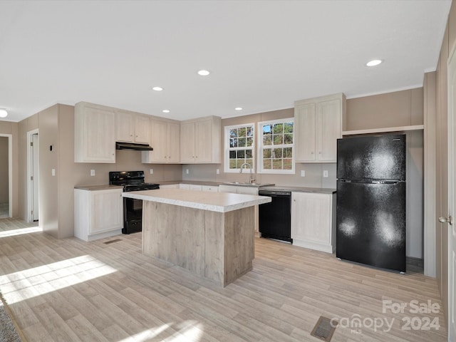 kitchen with black appliances, a kitchen island, light wood-type flooring, and sink