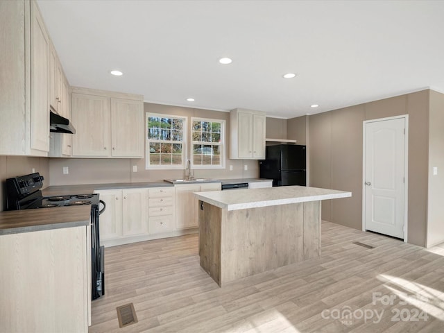 kitchen with sink, light hardwood / wood-style floors, a kitchen island, and black appliances