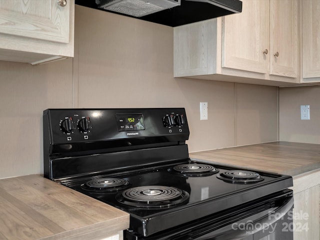 kitchen with black / electric stove, light brown cabinetry, wall chimney exhaust hood, and wooden counters