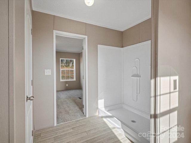 bathroom with a shower, hardwood / wood-style floors, and crown molding