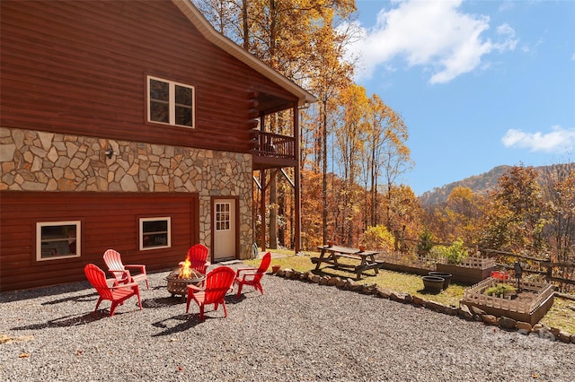 exterior space with a fire pit, a mountain view, and a balcony