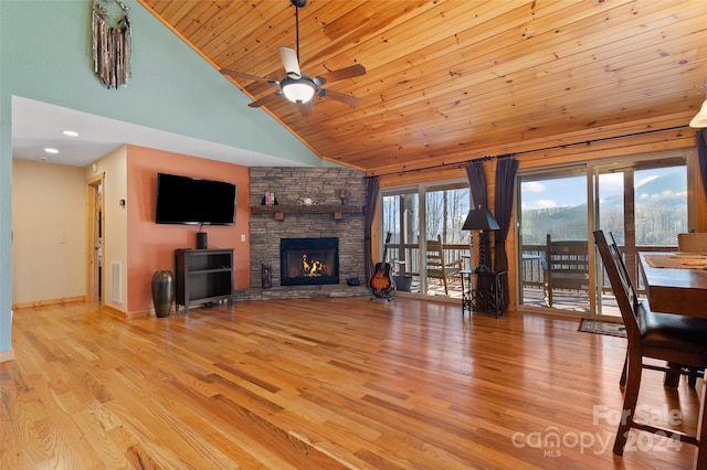 living room featuring a fireplace, light wood-type flooring, high vaulted ceiling, and ceiling fan