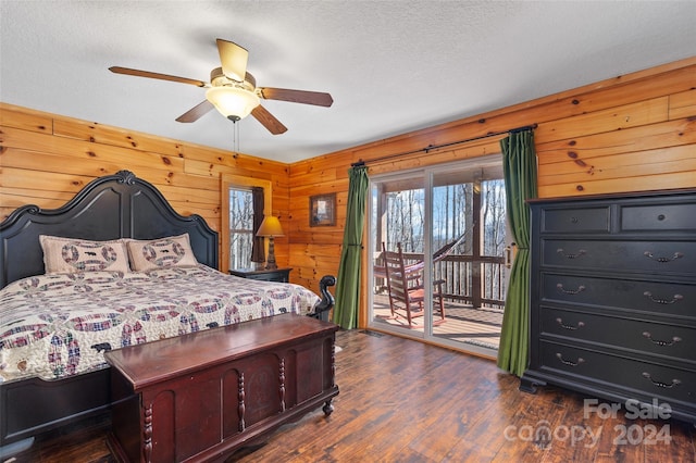 bedroom with ceiling fan, dark hardwood / wood-style flooring, a textured ceiling, access to outside, and wooden walls