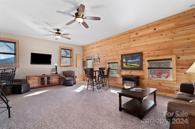 living room featuring carpet floors, ceiling fan, and wood walls