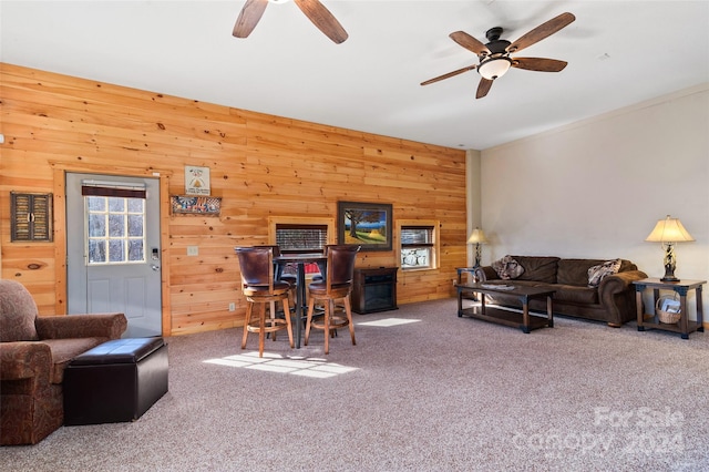 carpeted living room featuring ceiling fan and wood walls