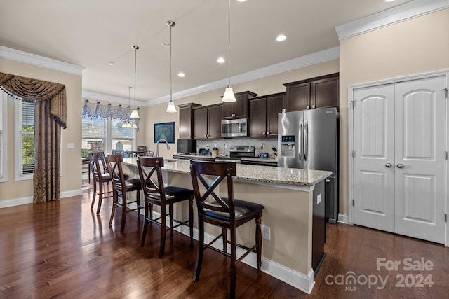 kitchen with stainless steel appliances, dark wood-type flooring, pendant lighting, a breakfast bar area, and a center island with sink