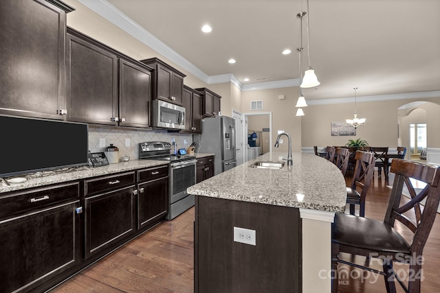 kitchen featuring sink, dark wood-type flooring, stainless steel appliances, a center island with sink, and ornamental molding