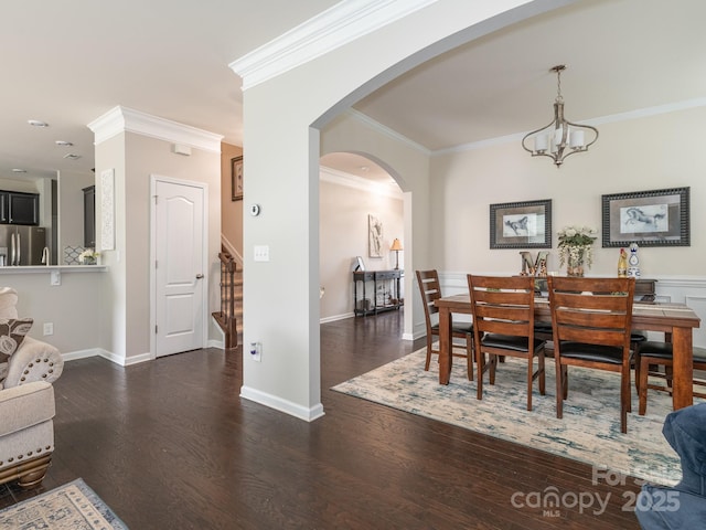 dining space featuring dark wood-type flooring, ornamental molding, and a notable chandelier