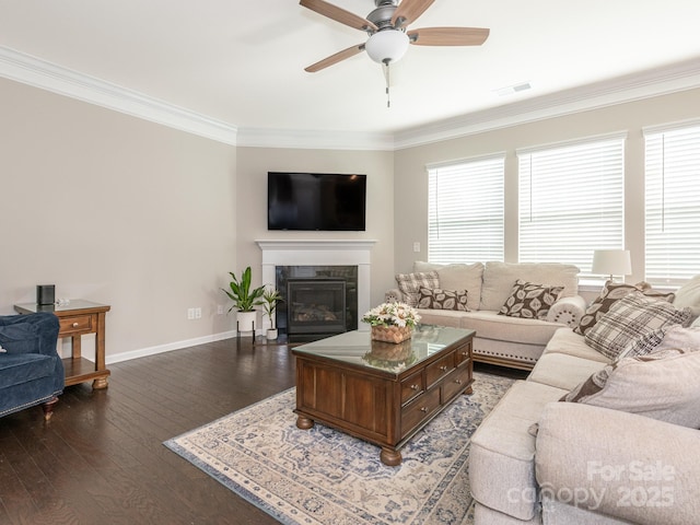 living room with ceiling fan, dark hardwood / wood-style flooring, ornamental molding, and a fireplace