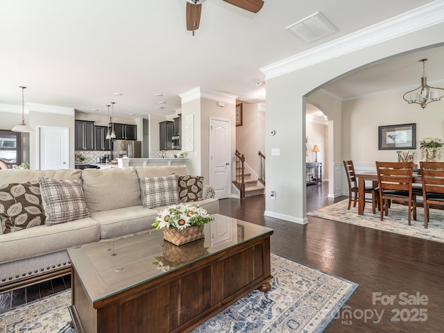 living room with dark hardwood / wood-style floors, crown molding, and ceiling fan with notable chandelier