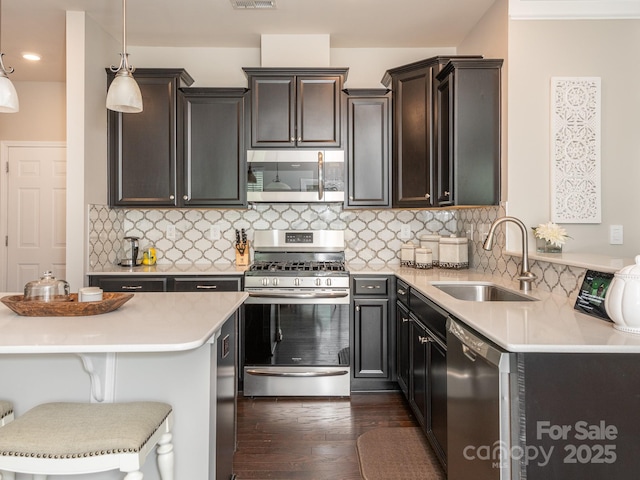 kitchen featuring sink, hanging light fixtures, a breakfast bar area, decorative backsplash, and stainless steel appliances