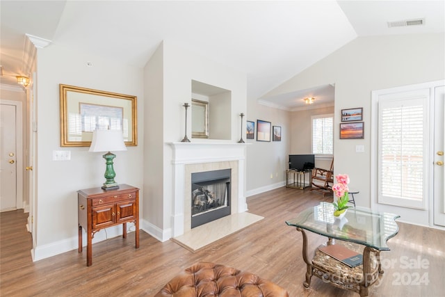 living room with light hardwood / wood-style flooring, lofted ceiling, and ornamental molding