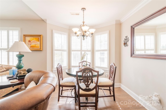 dining space with light hardwood / wood-style flooring, a chandelier, and ornamental molding