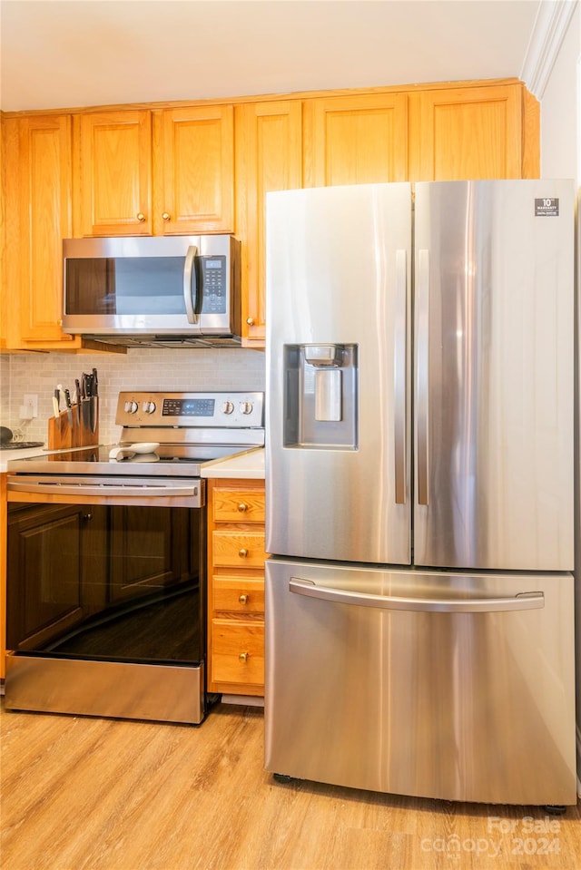 kitchen with backsplash, ornamental molding, stainless steel appliances, and light hardwood / wood-style flooring