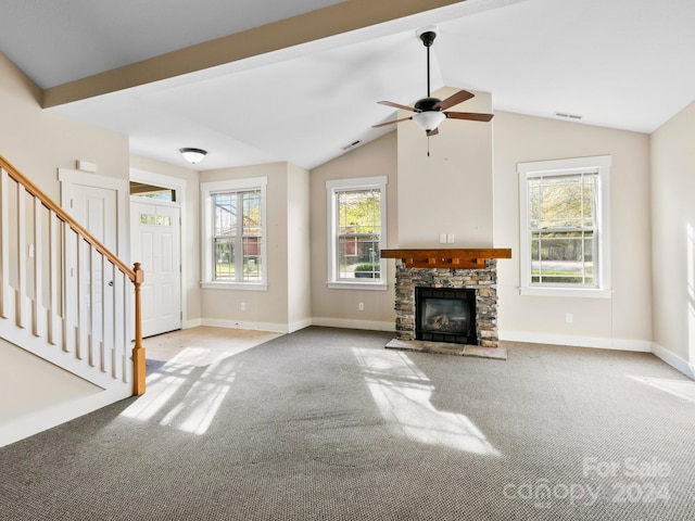 unfurnished living room featuring ceiling fan, a stone fireplace, lofted ceiling, and light carpet