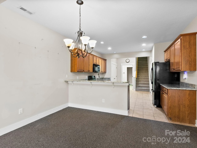 kitchen featuring kitchen peninsula, light stone counters, a breakfast bar area, and black appliances