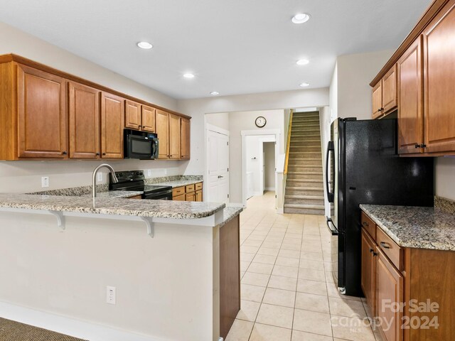 60 Westfield Way, Candler, NC 28715 - kitchen featuring black appliances, a peninsula, a breakfast bar, brown cabinetry, and recessed lighting